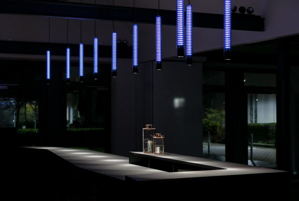 Blaue LEDs hinter Textil in Glasleuchten abgehängt und über einer Bar montiert