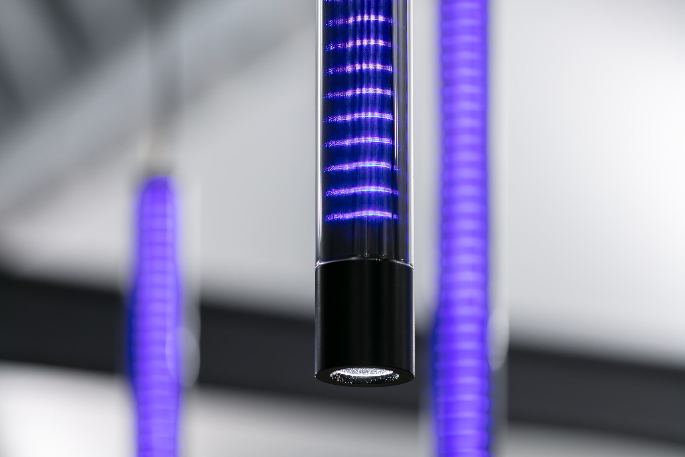 Detailaufnahme einer Pendelleuchte aus Glas in lila LEDs leuchtend