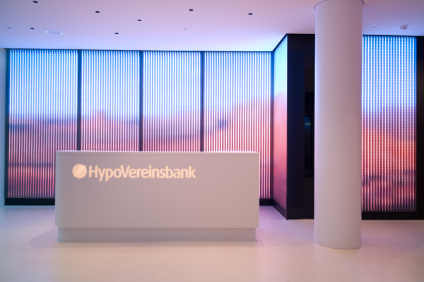 Large-area framesystems backlit with LEDs that create a dynamic lighteffect. ETTLIN LUX® light technical fabric enables a very special light effect in the entrance area of the HypoVereinsbank.